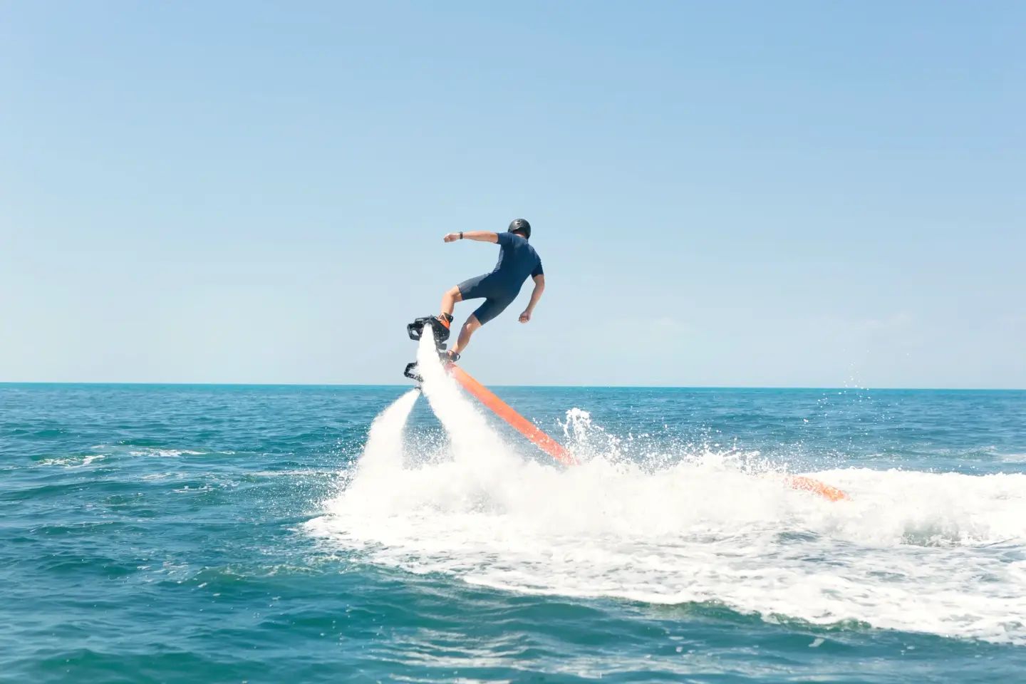 Flyboard rider lifted above the sea on two jets of water